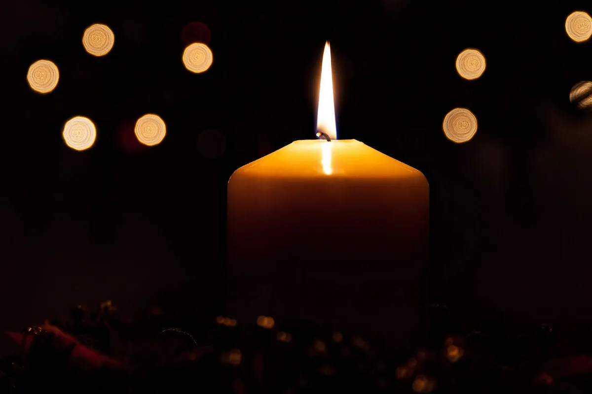 A lit candle sits against a dark background